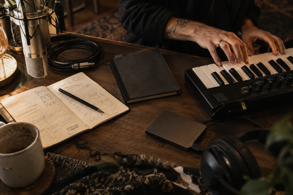Appunti, microfono e tastiera in una rappresentazione del lavoro creativo in studio.